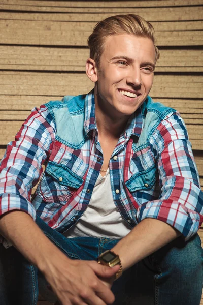 Smiling man sitting in studio background looking away — Stock Photo, Image