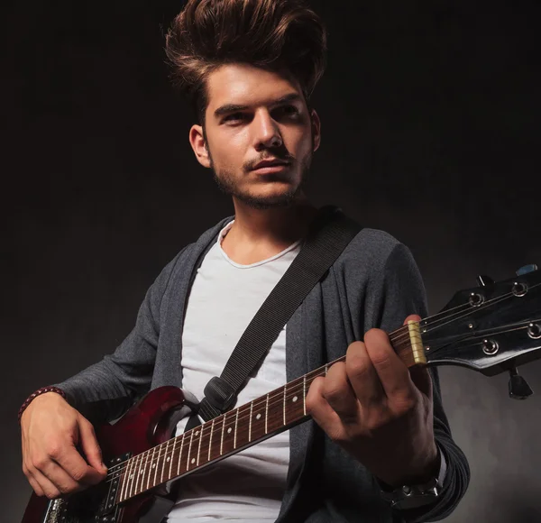 Indie kunstenaar gitaarspelen in studio achtergrond — Stockfoto
