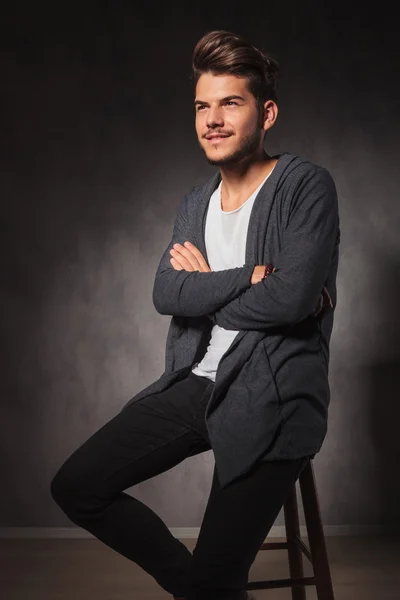 Young man posing in studio hands crossed while sitting — Stock Photo, Image