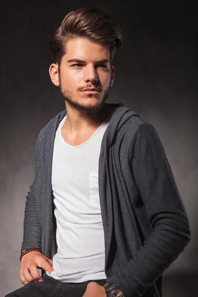 Retrato de un joven elegante posando en el estudio mientras está sentado — Foto de Stock