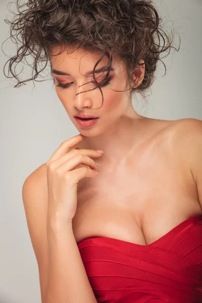 Модель в красном платье, прикасающаяся к подбородку — стоковое фото