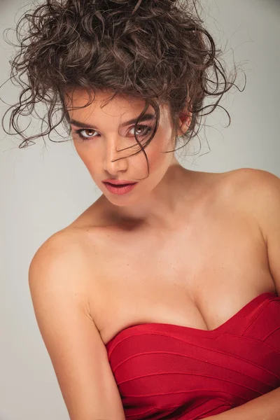 Modelo rizado en vestido rojo posando mientras se apoya en el lado —  Fotos de Stock