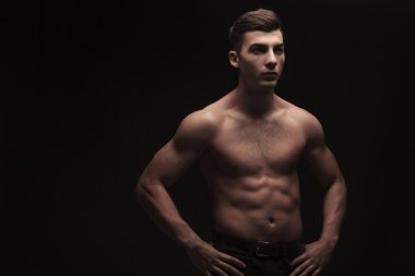 genç erkek ile karanlık studio arka plan esneme bel üzerinde eller