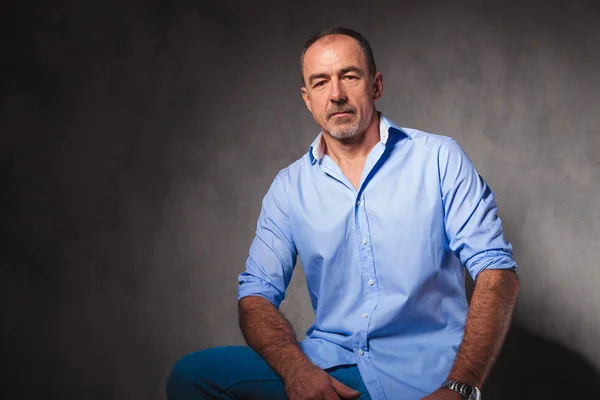 Hombre de negocios en la pose camisa casual en el fondo del estudio sentado —  Fotos de Stock