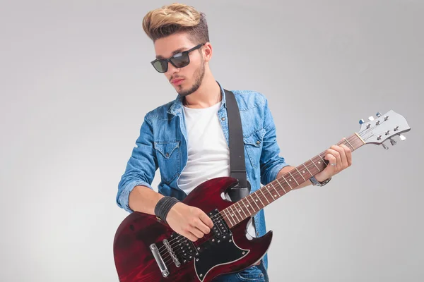 Hipster playing the guitar in studio background Stock Image