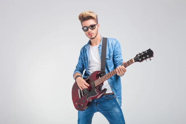 Artist playing guitar in studio background while wearing sunglas Stock Picture