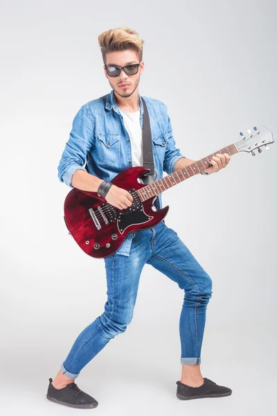 Artist playing guitar in studio background while posing Stock Image