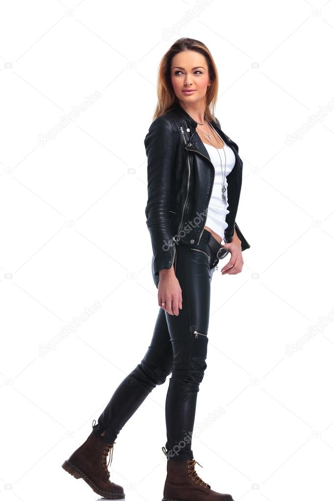 Girl in leather jacket pose walking in studio background while l ...