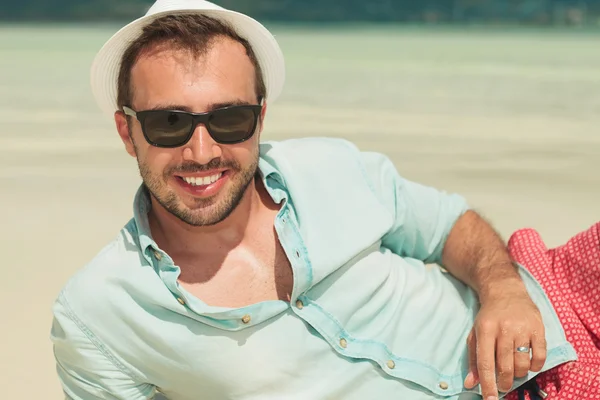 웃는 남자 선글라스를 착용 하 고 해변에 내려 놓고 — 스톡 사진