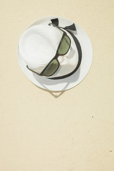 Sombrero con correa negra y gafas de sol en la playa — Foto de Stock