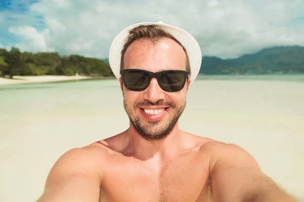 Homme prenant un selfie sur la plage tout en portant des nuances et un chapeau — Photo