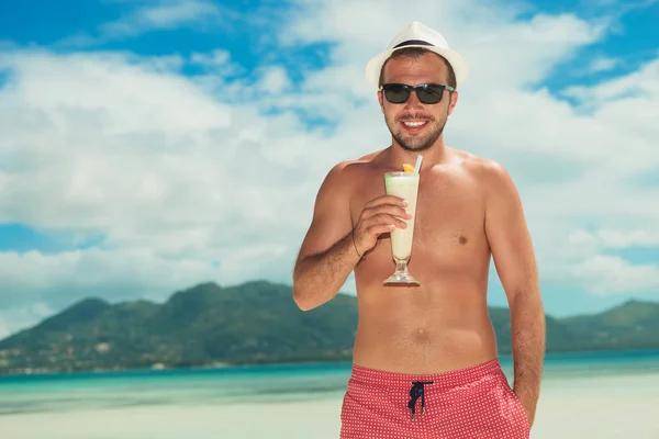 Чоловік носить відтінки і п'є коктейль на пляжі — стокове фото