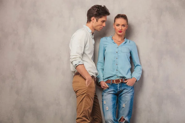 Casal casual pose em estúdio fundo com as mãos nos bolsos — Fotografia de Stock