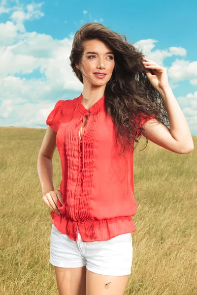 Mujer vistiendo blusa roja y pantalones cortos blancos mientras mira hacia otro lado — Foto de Stock