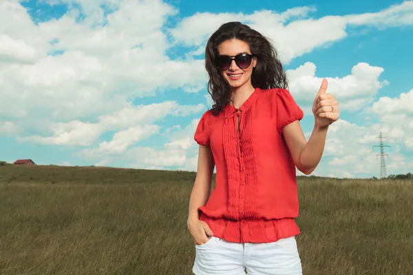 Girl posing in nature with hand in pocket while showing victory — Stock Photo, Image
