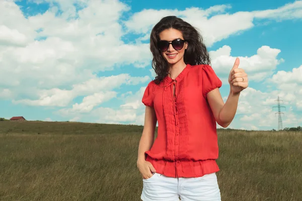 Menina posando na natureza com a mão no bolso, mostrando vitória — Fotografia de Stock