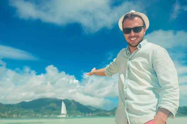 Smiling man presenting from a boat on the exotic sea — Stock Photo, Image