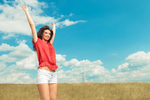 Girl jumping in the fields with her hands raised in the air — Stock Photo, Image