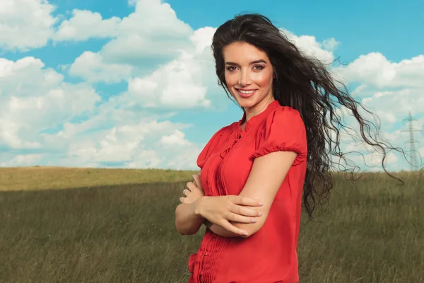 Fille avec les mains croisées souriant dans les champs — Photo