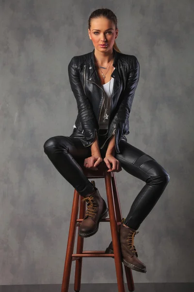 Attractive rocker woman in leather posing seated in studio — Stock Photo, Image