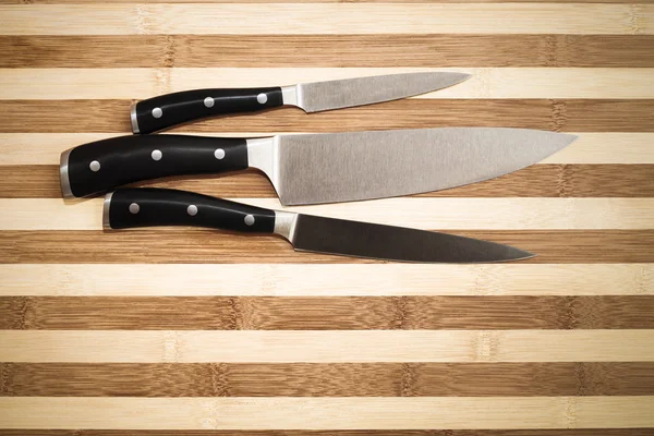 Three kitchen knives over  bamboo  cutting board — Stock Photo, Image