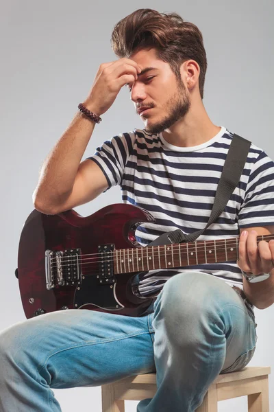 Chitarrista che suona lo strumento seduto mentre pensa — Foto Stock