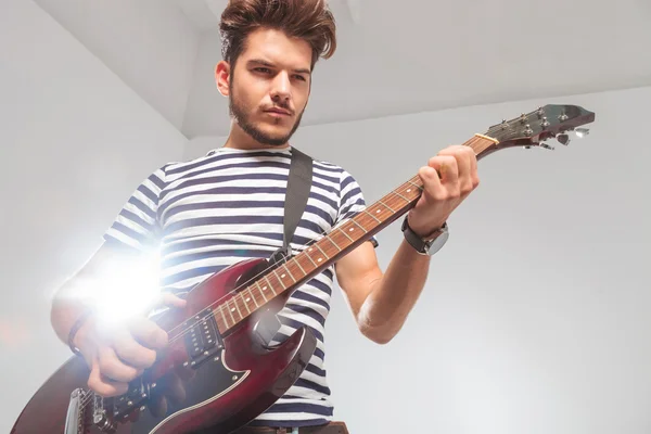 Posa rocker guardando verso il basso durante la riproduzione della chitarra elettrica — Foto Stock