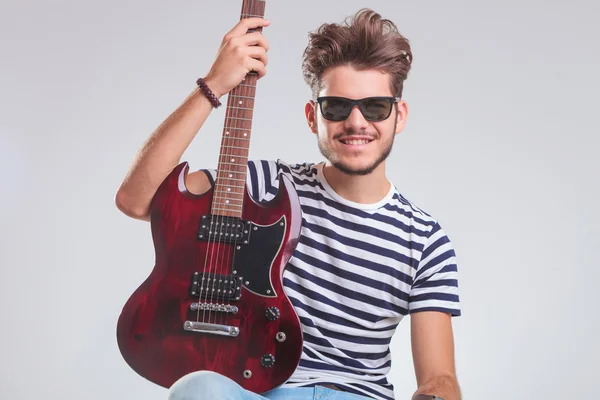 Rocker posing in studio with electric guitar in his lap — Zdjęcie stockowe