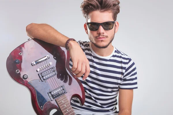 Rocker pose while resting on electric guitar in studio — Stock Fotó