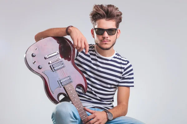 Sentado homem com guitarra descansando enquanto posando em estúdio — Fotografia de Stock