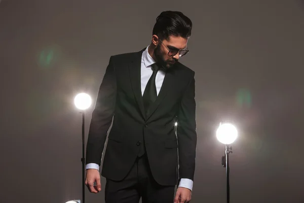 Man in business suit looking down in studio with spotlights on — ストック写真