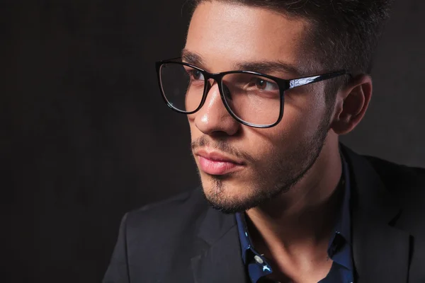 Hombre inteligente con gafas en el fondo del estudio mientras mira awa —  Fotos de Stock