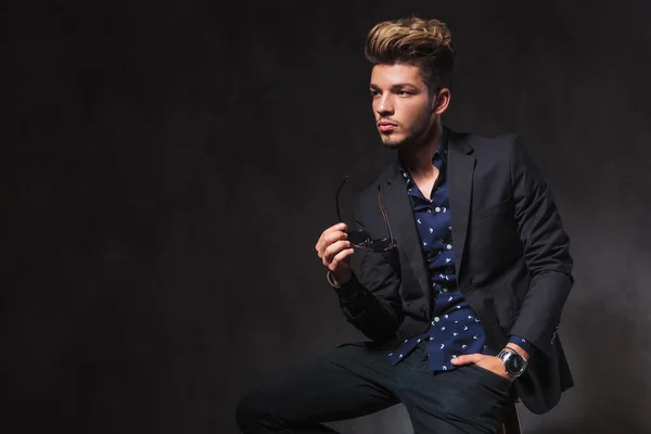 Model seated in dark studio background looking away while taking — Stockfoto