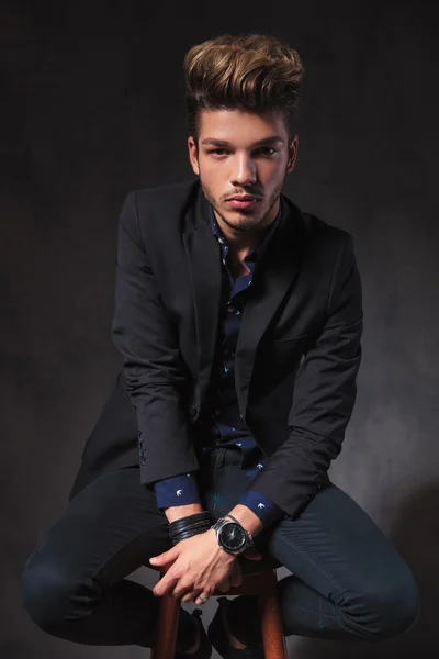 Hombre posando sentado en oscuro estudio fondo vistiendo de negro — Foto de Stock