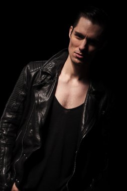 rocker in black leather jacket posing leaning one side