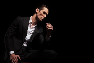 man in black looking away while seated