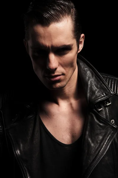 Close portrait of rocker in leather jacket posing in dark — Stok fotoğraf