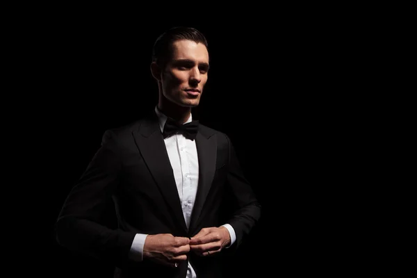 Model in black tux with bowtie posing in dark studio — Stock fotografie