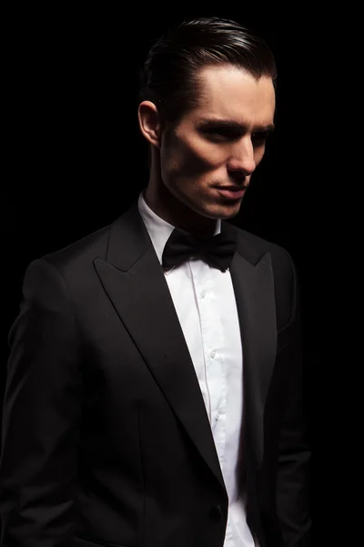 Classy man in tuxedo looking away in dark studio — Stock Photo, Image