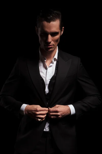 Businessman in suit posing in studio background closing his jack — Zdjęcie stockowe