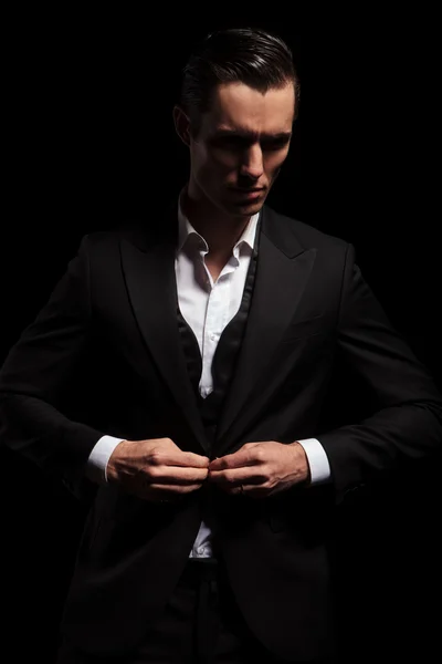 Elegant man in black tuxedo posing in dark studio — Stock Photo, Image