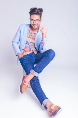 handsome man posing seated with legs crossed