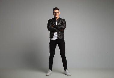 man in leather jacket posing in studio with hands crossed