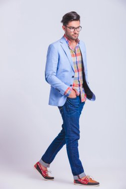 casual guy walking in studio background with hands in pockets