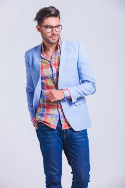 fashionable man walking in studio with hand in back pocket 