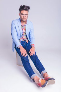 man wearing glasses seated on chair looking at the camera