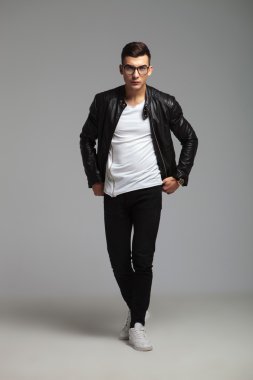 man wearing glasses walking in studio while arranging his shirt