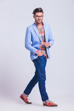 young man wearing glasses walking in studio