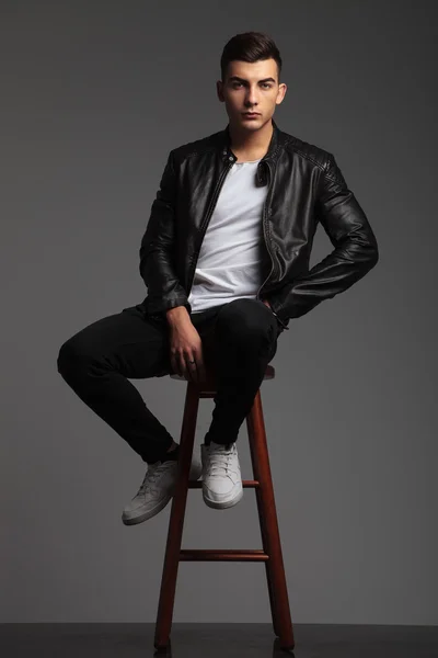 Modelo em preto posando sentado com a mão na cintura — Fotografia de Stock