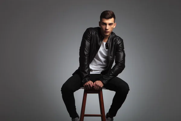 Model seated on stool with hands between his legs — Stock fotografie